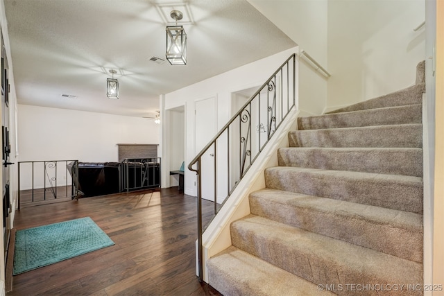 stairs featuring wood-type flooring and ceiling fan