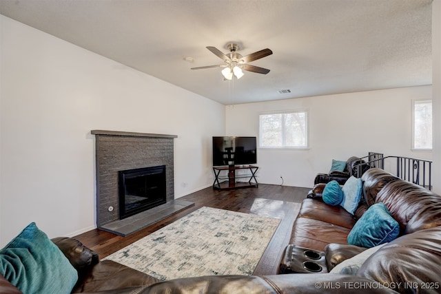 living room featuring ceiling fan, dark hardwood / wood-style floors, and a tile fireplace