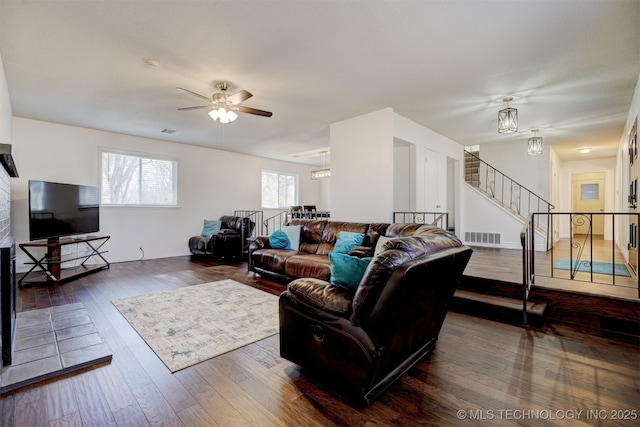 living room with dark wood-type flooring and ceiling fan with notable chandelier