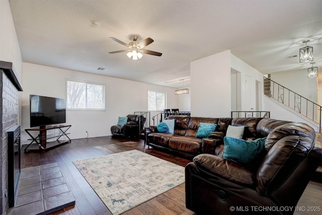 living room featuring dark hardwood / wood-style flooring, a brick fireplace, a textured ceiling, and ceiling fan