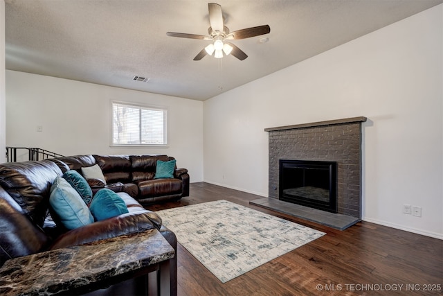 living room with dark hardwood / wood-style flooring, a textured ceiling, a fireplace, and ceiling fan