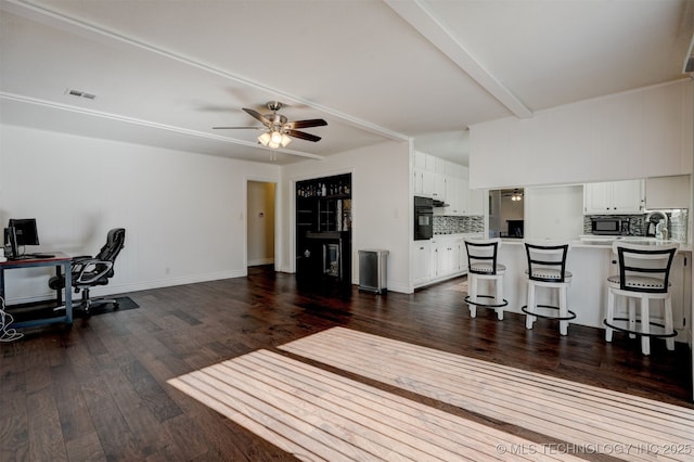 office area featuring ceiling fan, dark hardwood / wood-style floors, and beam ceiling