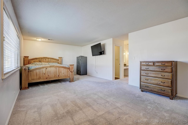 bedroom with ensuite bath and light carpet