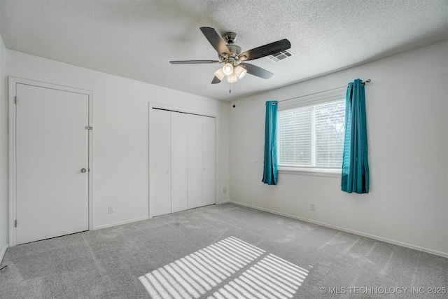 unfurnished bedroom with light carpet, a textured ceiling, ceiling fan, and a closet