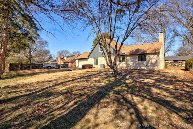 back of property with a garage and a lawn