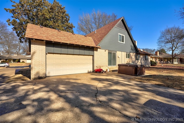 view of home's exterior with a garage and a hot tub