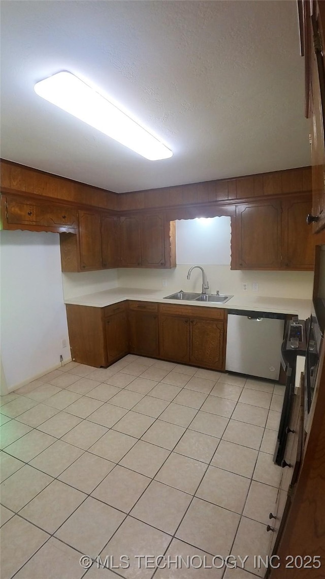 kitchen featuring light tile patterned flooring, stainless steel dishwasher, and sink