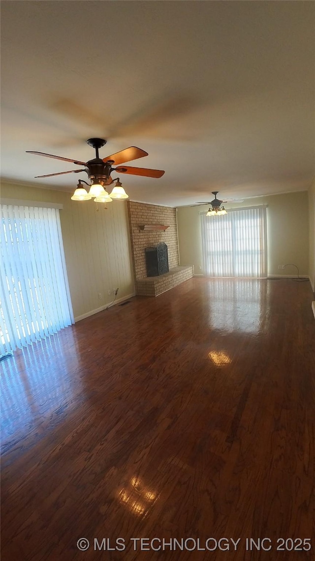 unfurnished living room with hardwood / wood-style flooring, a brick fireplace, and ceiling fan