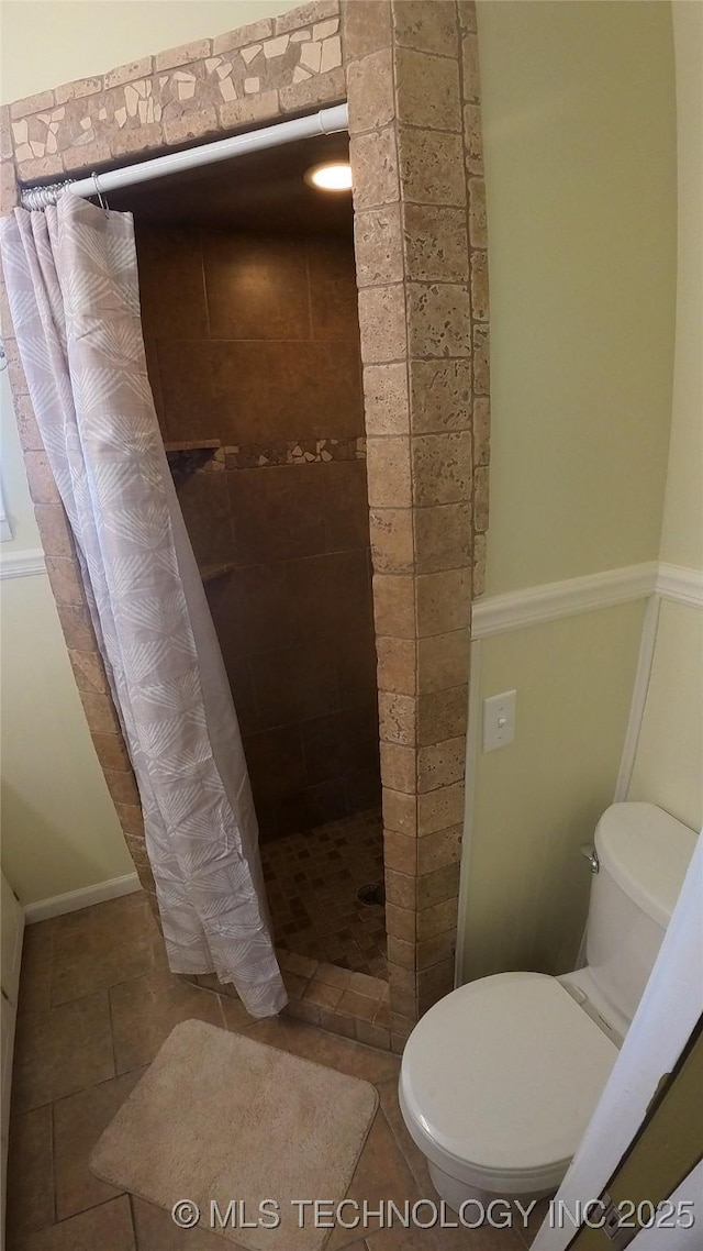 bathroom with curtained shower, tile patterned floors, and toilet