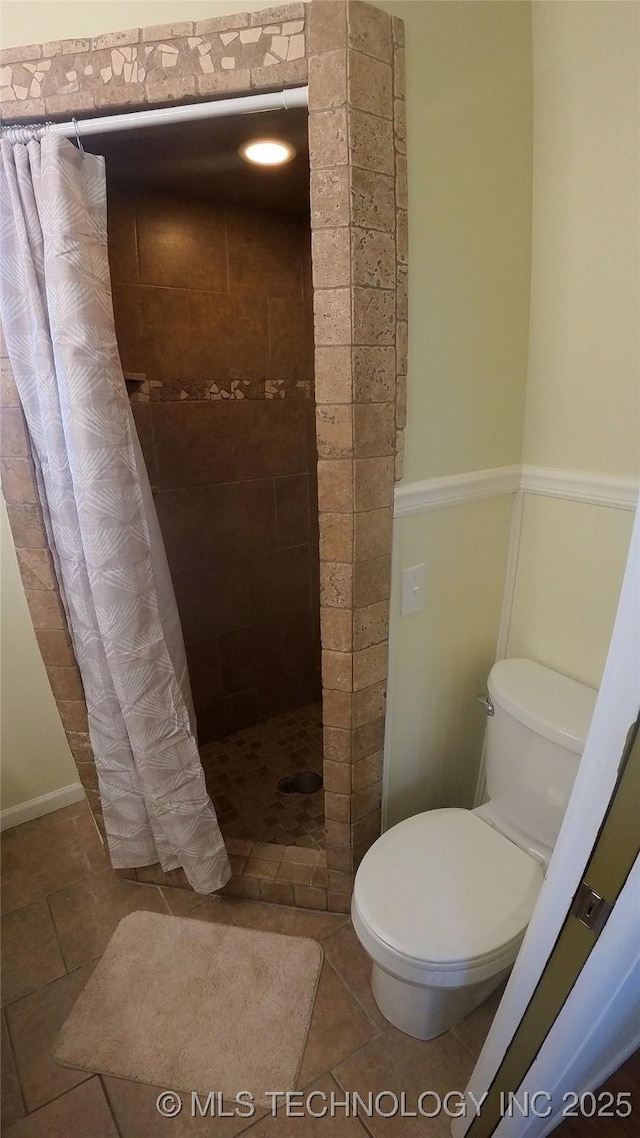 bathroom featuring tile patterned flooring, curtained shower, and toilet