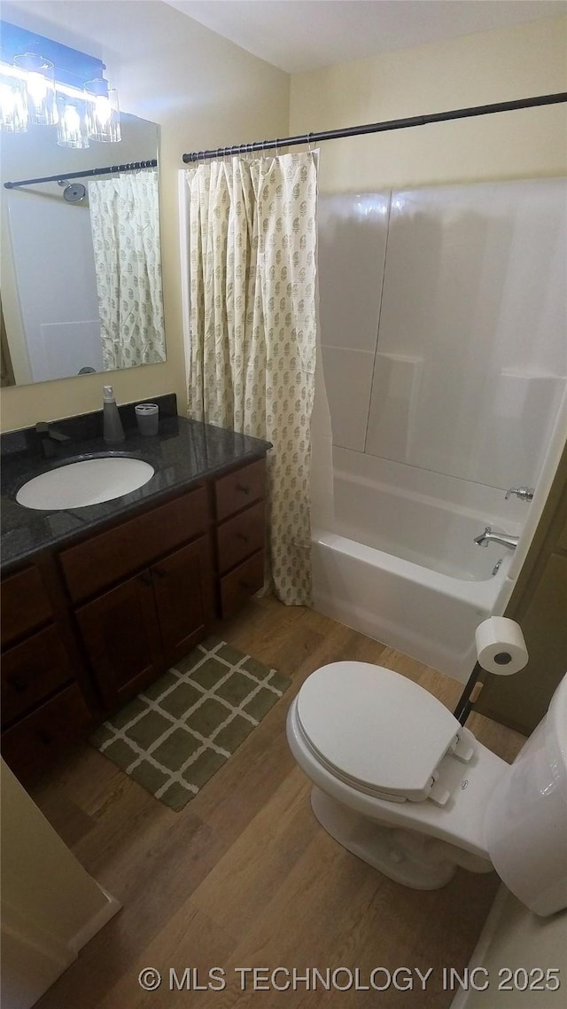 full bathroom featuring shower / tub combo with curtain, vanity, hardwood / wood-style flooring, and toilet