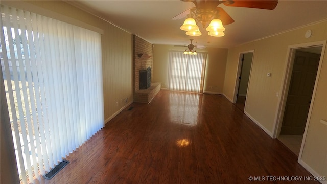 unfurnished living room featuring ceiling fan, dark hardwood / wood-style floors, crown molding, and a fireplace