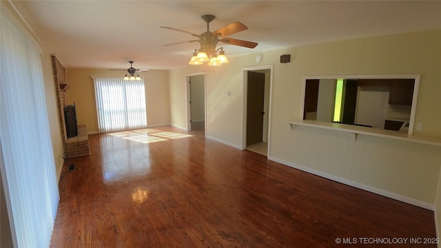 unfurnished room with a brick fireplace, hardwood / wood-style flooring, and ceiling fan