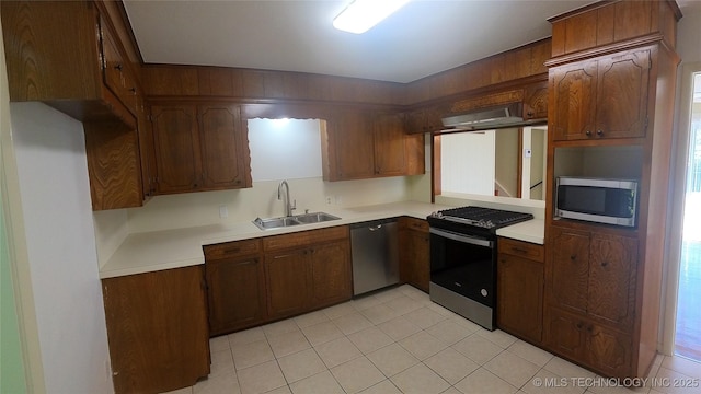 kitchen featuring sink, light tile patterned floors, wall chimney range hood, and stainless steel appliances