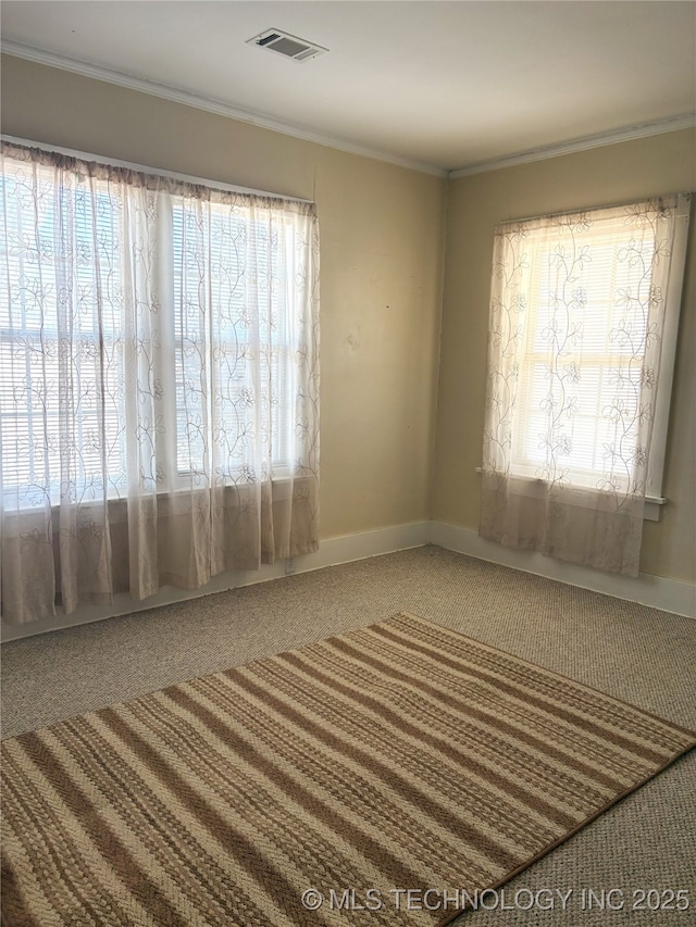 empty room with visible vents, baseboards, and crown molding