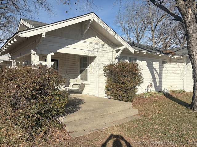 view of property exterior with covered porch and a yard