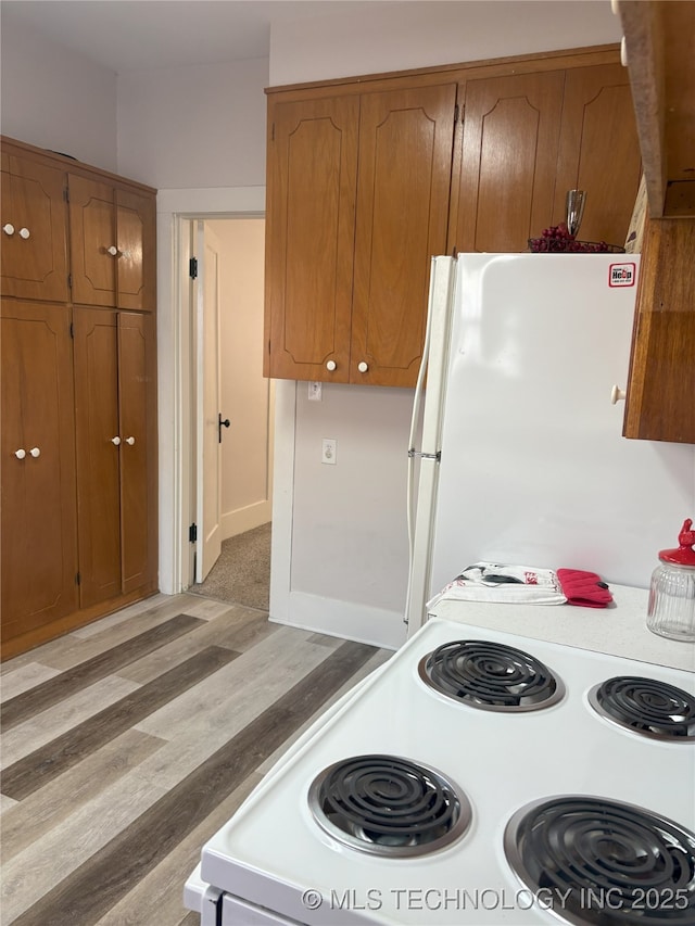 kitchen with white appliances, light wood-style flooring, light countertops, and brown cabinets