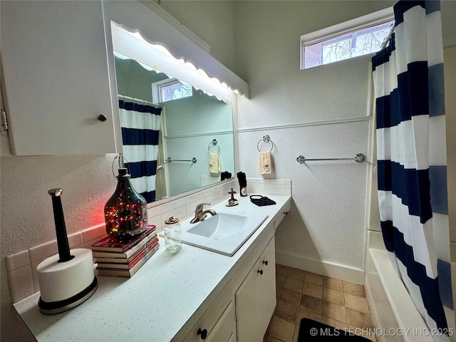 bathroom with vanity, a textured wall, and baseboards