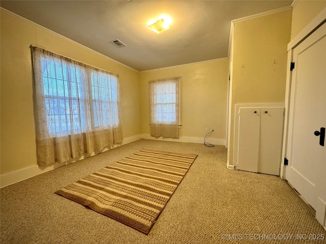 unfurnished bedroom featuring visible vents, carpet flooring, baseboards, and ornamental molding