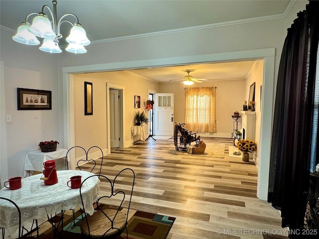 dining area featuring crown molding, ceiling fan with notable chandelier, baseboards, and light wood finished floors