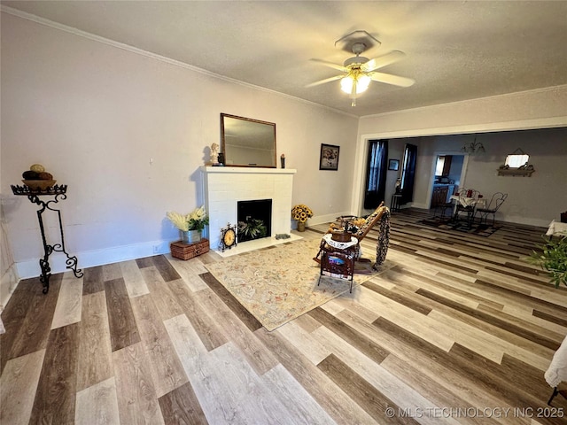 living room featuring hardwood / wood-style flooring, ceiling fan, crown molding, and a textured ceiling