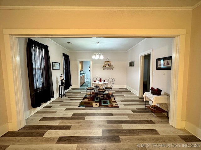 dining area with an inviting chandelier, crown molding, wood finished floors, and baseboards