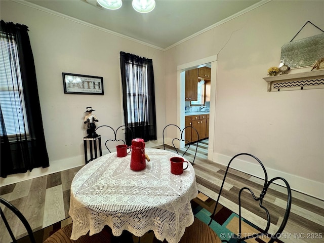 dining room with wood finished floors, baseboards, and ornamental molding