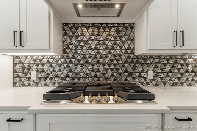 kitchen featuring exhaust hood, stainless steel gas cooktop, decorative backsplash, and white cabinets