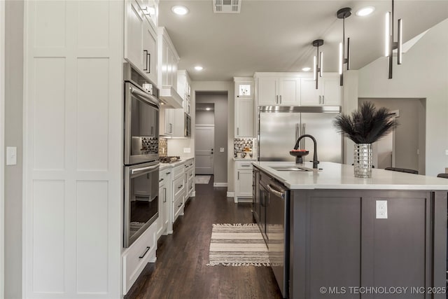 kitchen featuring hanging light fixtures, an island with sink, appliances with stainless steel finishes, and white cabinets