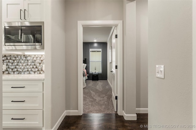 hallway featuring crown molding and dark colored carpet