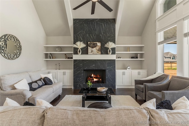 living room featuring dark wood-type flooring, built in features, a premium fireplace, and ceiling fan