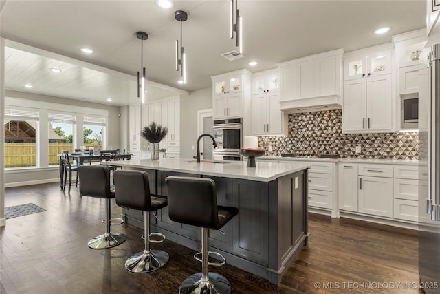 kitchen featuring white cabinetry, sink, decorative light fixtures, and a kitchen island with sink