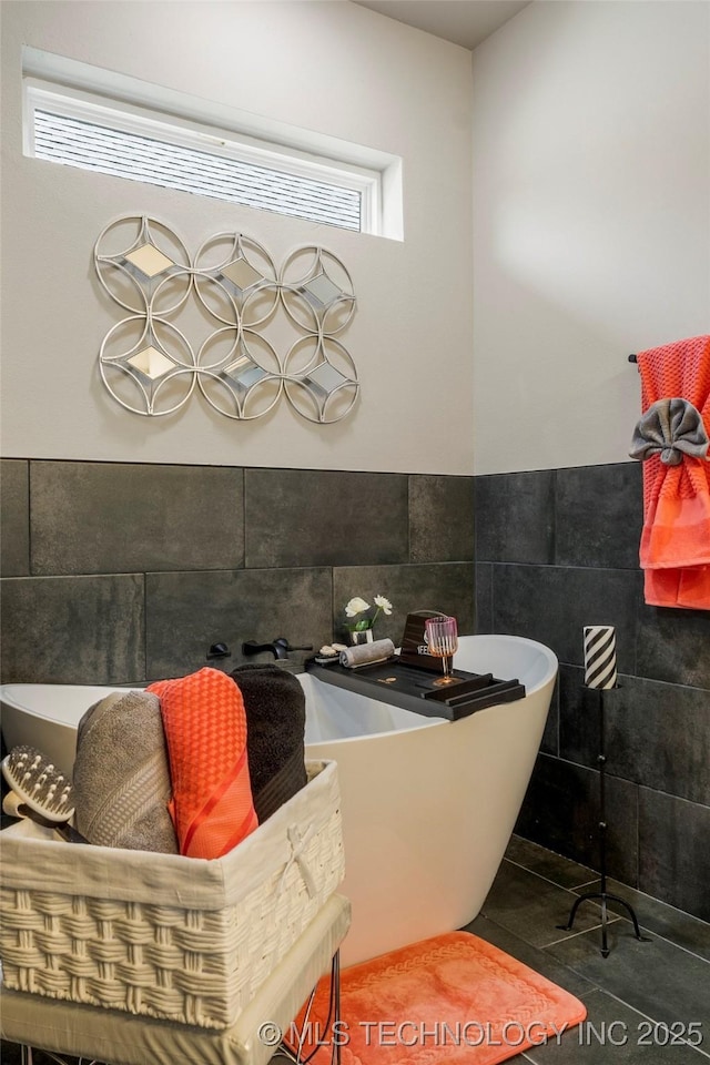 bathroom with tile walls, tile patterned flooring, a wealth of natural light, and a tub