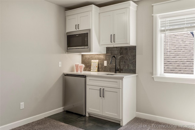 kitchen featuring built in microwave, white cabinetry, fridge, and sink