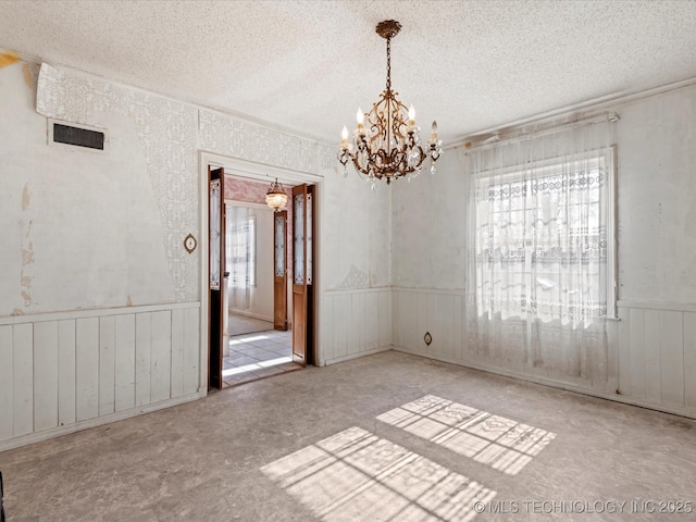 empty room featuring a notable chandelier and a textured ceiling