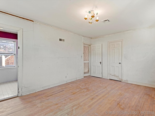 spare room featuring a chandelier and light wood-type flooring