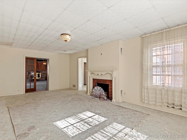 unfurnished living room featuring a brick fireplace and french doors