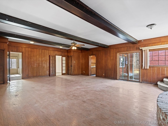 unfurnished living room with beamed ceiling, ceiling fan, light wood-type flooring, and wood walls