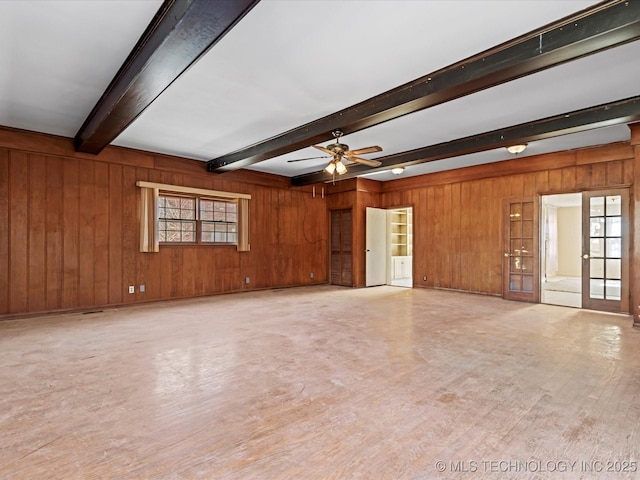 unfurnished living room with ceiling fan, wooden walls, hardwood / wood-style floors, and beam ceiling