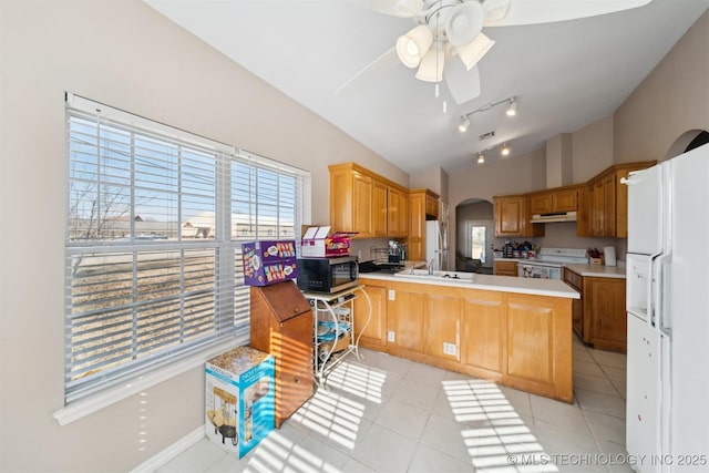 kitchen with sink, white appliances, light tile patterned flooring, vaulted ceiling, and kitchen peninsula