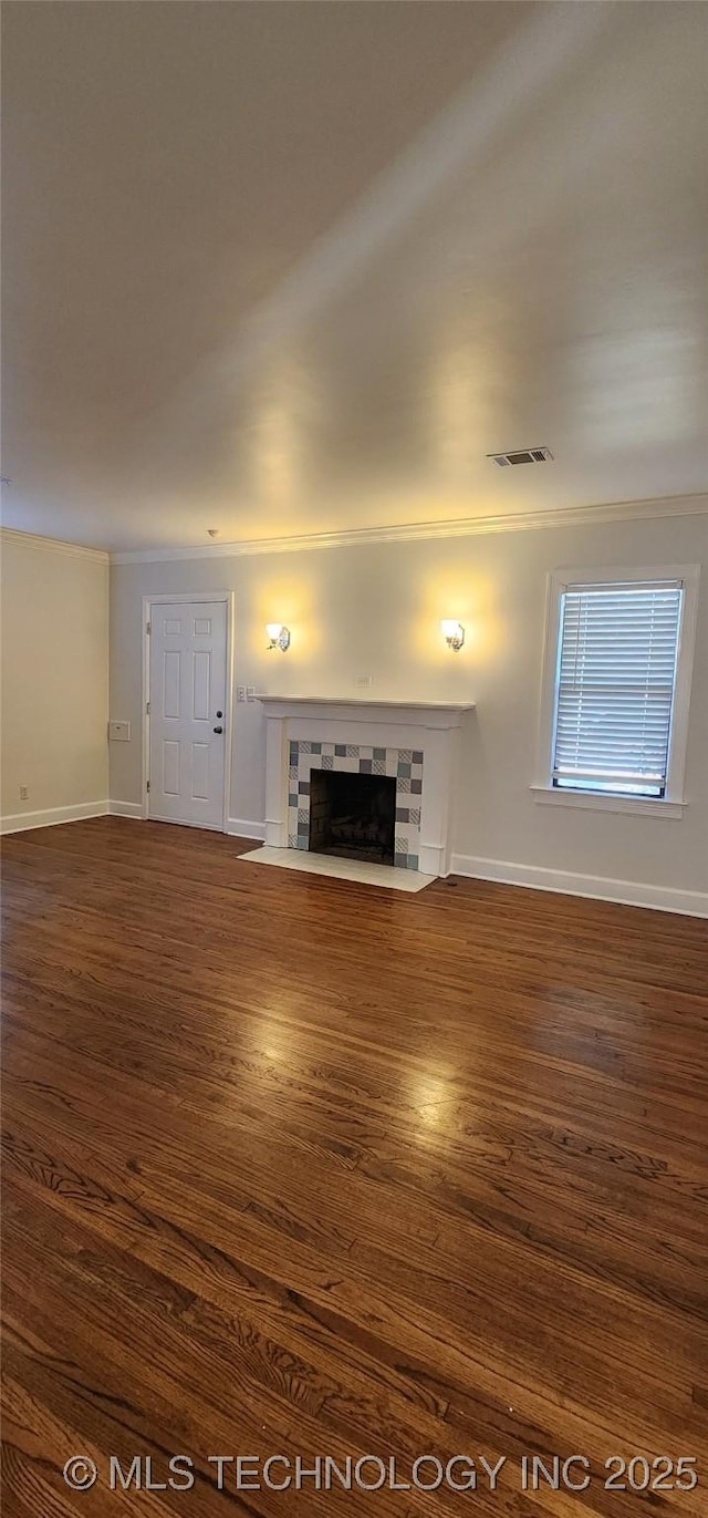 unfurnished living room featuring a tile fireplace and dark hardwood / wood-style floors