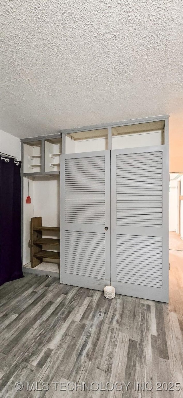 unfurnished bedroom with hardwood / wood-style floors, a textured ceiling, and a closet