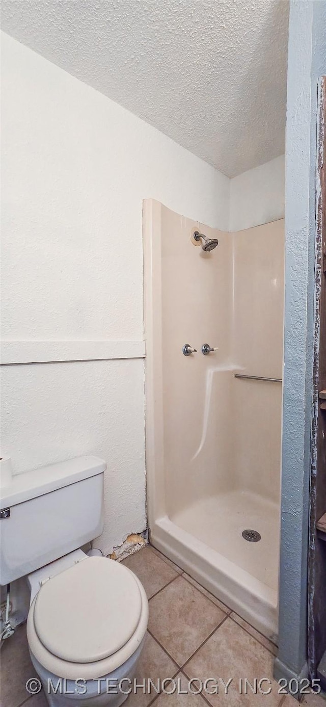 bathroom featuring toilet, tile patterned floors, a textured ceiling, and walk in shower