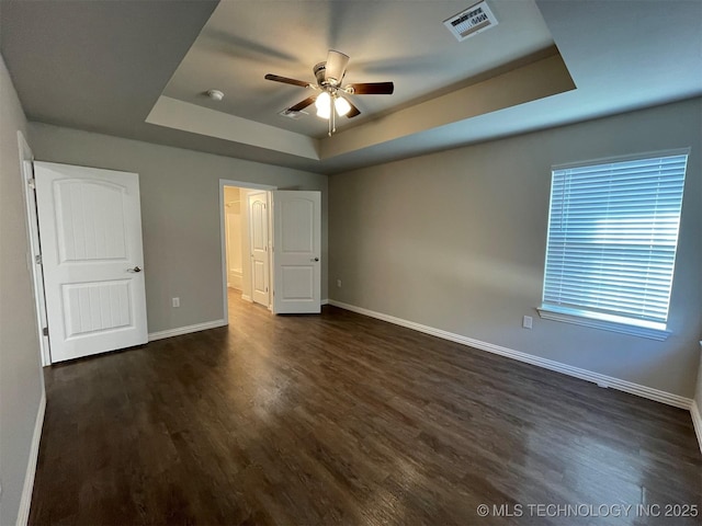 unfurnished bedroom featuring a tray ceiling, dark hardwood / wood-style floors, and ceiling fan