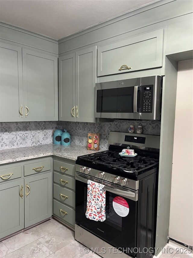 kitchen with tasteful backsplash, stainless steel appliances, light stone countertops, and light tile patterned flooring