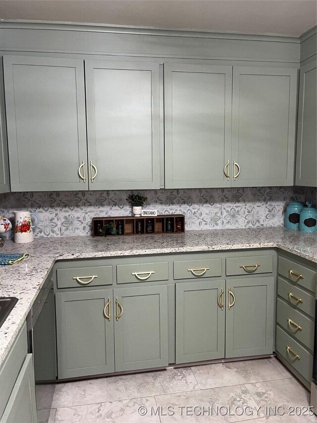 kitchen featuring backsplash, light stone countertops, green cabinetry, and dishwasher