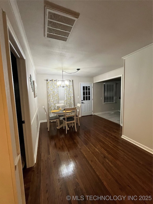 unfurnished dining area with ornamental molding, dark wood-type flooring, and an inviting chandelier