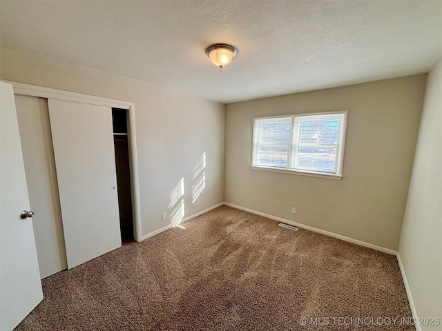 unfurnished bedroom with carpet floors, a textured ceiling, and a closet