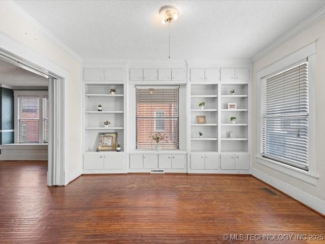 unfurnished living room with ornamental molding, built in features, and a textured ceiling