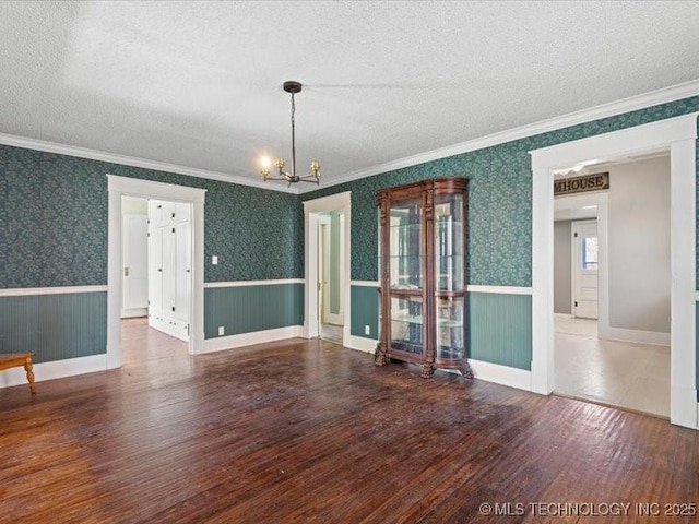 interior space featuring hardwood / wood-style floors, a textured ceiling, ornamental molding, and a chandelier